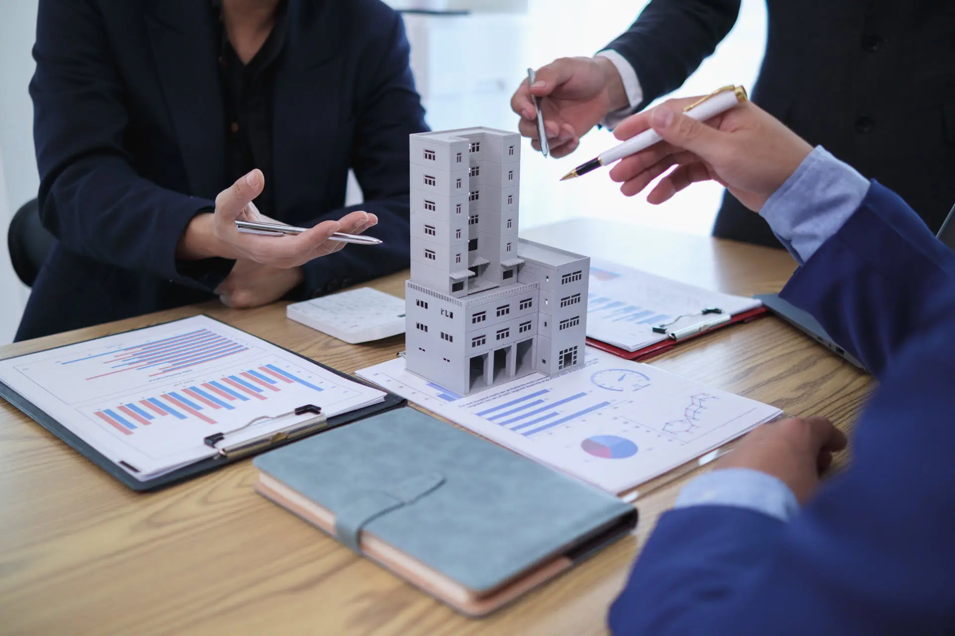 Business meeting with building model on table.