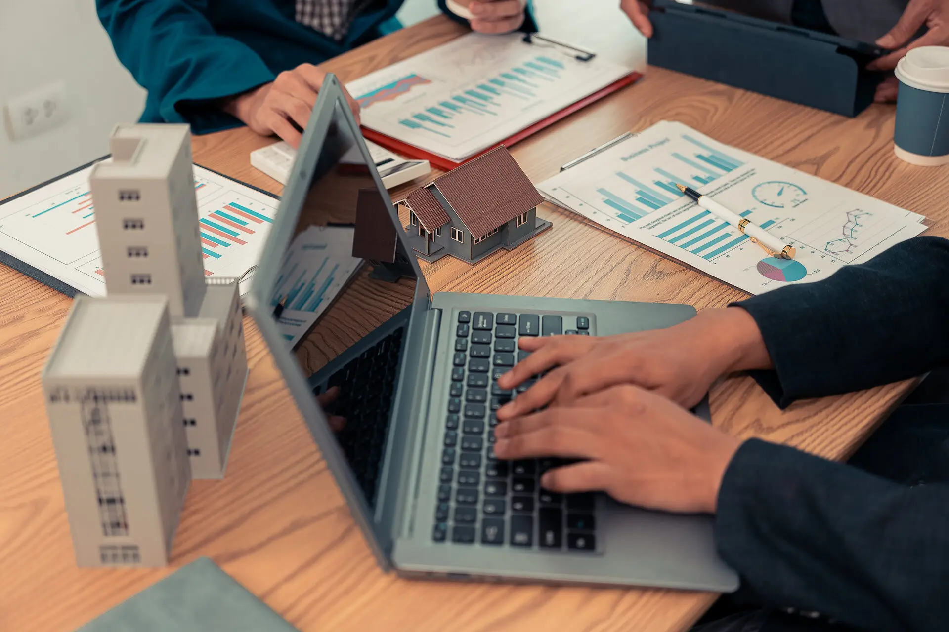 Person working on laptop, real estate documents.