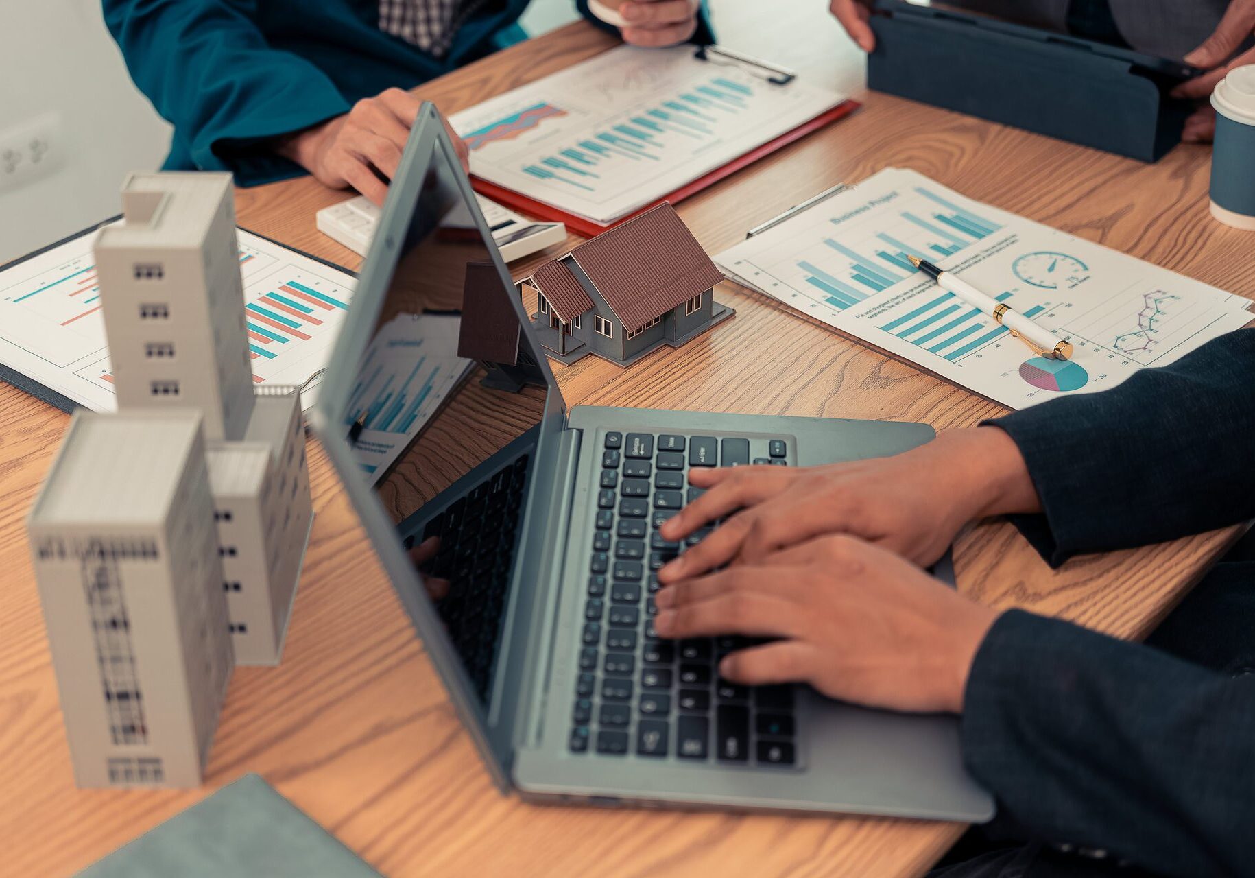 Person working on laptop, real estate documents.